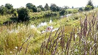a casual young guy spies on a naked milf sunbathing by the river