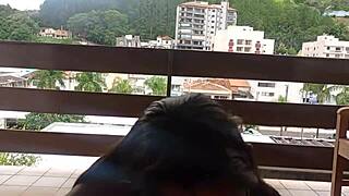 Married woman with young man on balcony, street people watching live during day.