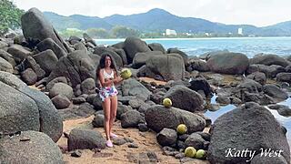 A young woman finds a coconut on a public beach and rubs its content on her body