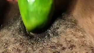 Close up of a webcam showing an amateur BDSM scene with a cucumber and a squirt