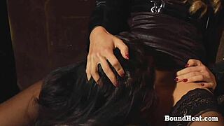 Naughty lesbian slave bound and licking her mistress's pussy on knees.