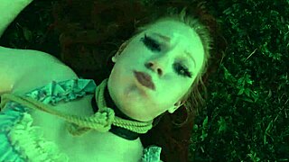 Submissive woman crawls from lagoon in humiliation scene.