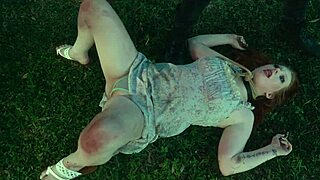 Submissive woman crawls from lagoon in humiliation scene.