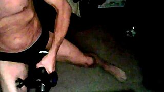 percussion massager vibes on thigh while sitting on stool in briefs