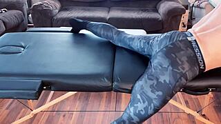 muscular bodybuilder stretches skinny neighbor on massage desk in tight leggings and socks