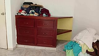 Chubby amateur folds clothes while tidying her messy room.
