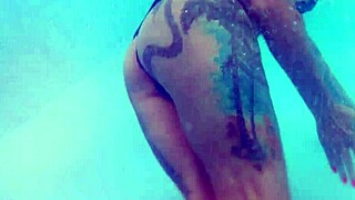 Melissa lounges as tattooed milf mermaid by pool with brown eyes
